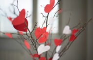 Twigs in a vase with red and white paper hearts on them.