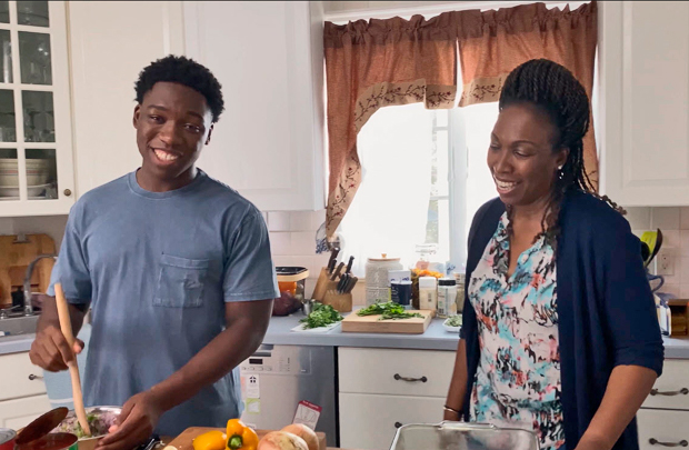 Teen son and mother standing in kitchen.