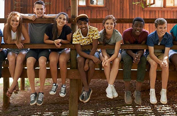 Group of teens sitting on fence.