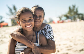Portrait of grandmother and granddaughter embracing at the beach