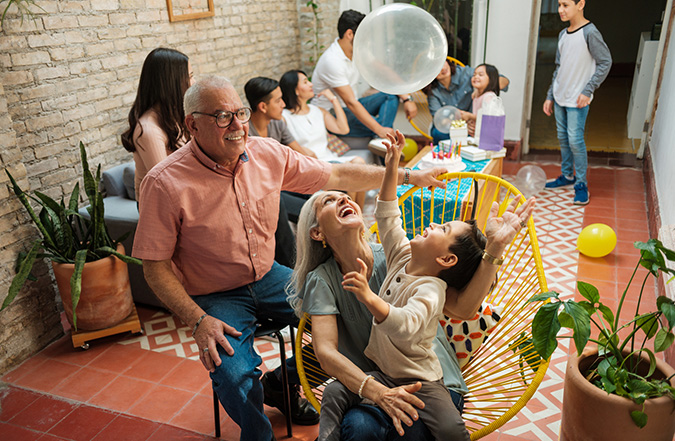 Grandparents playing with a child at a celebration with balloons