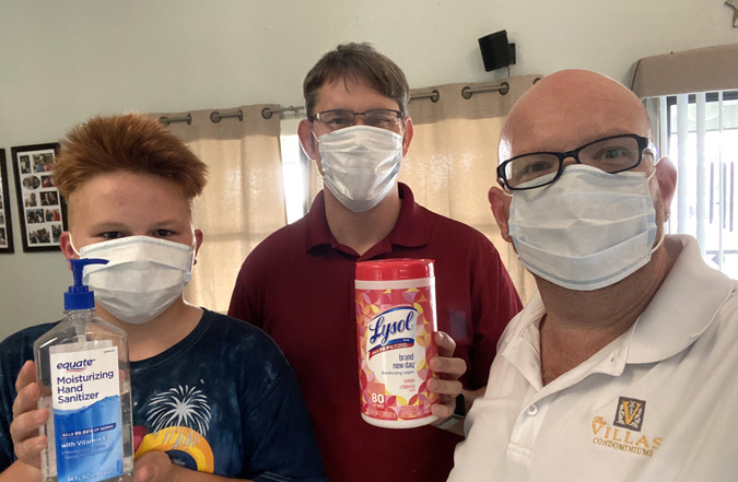 A family of two dads and their 13-year-old son wear masks and display pandemic goods.